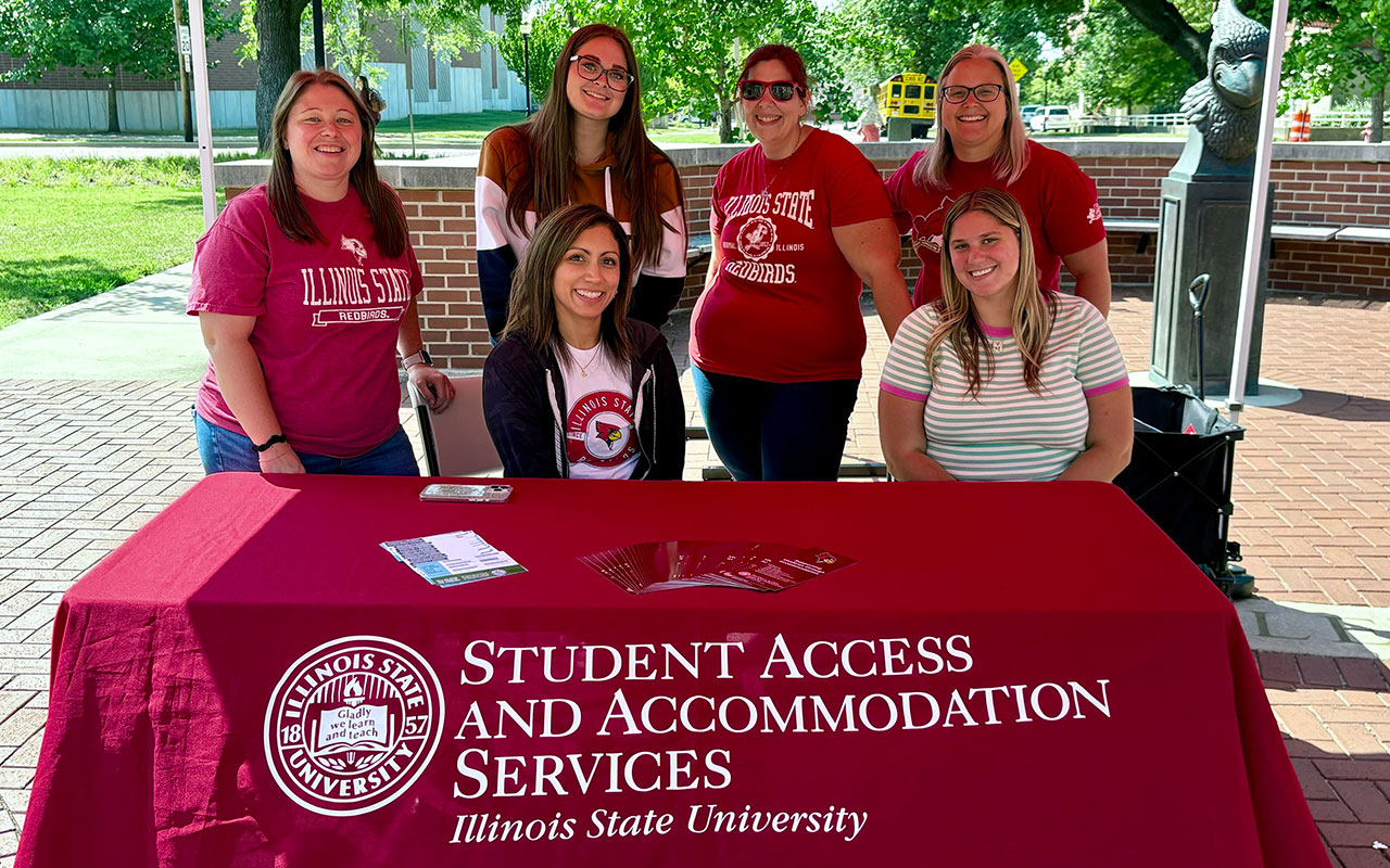 A group of accessibility staff members standing behind promotional table