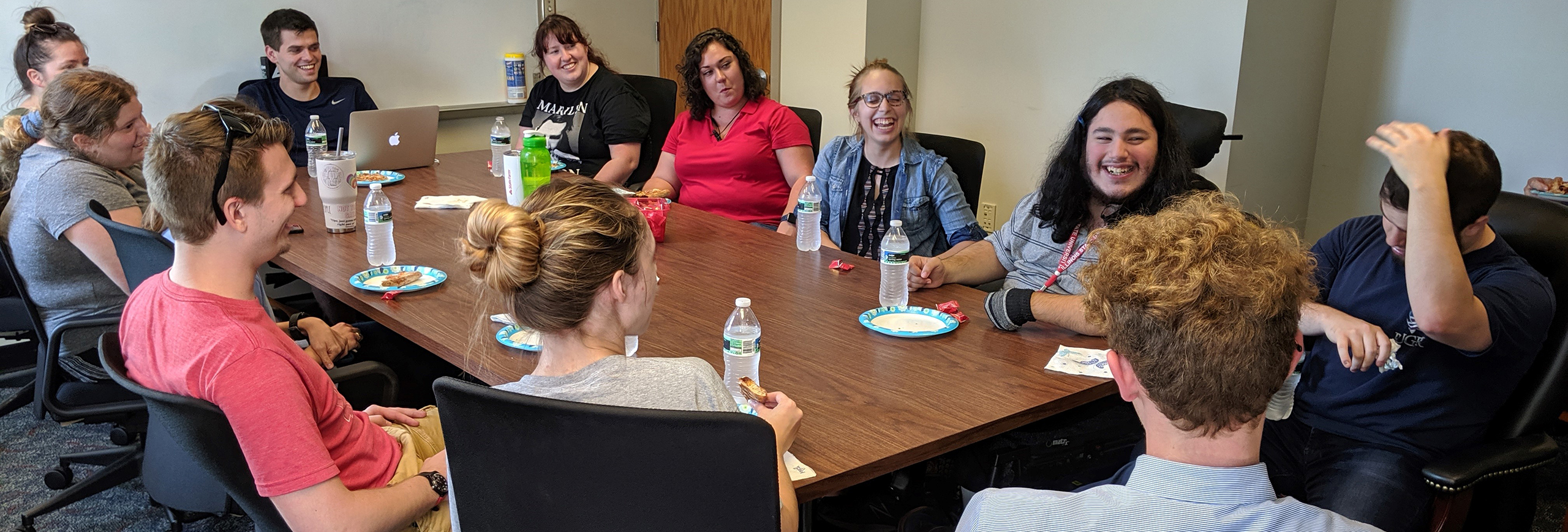 Students laughing together at a conference table.